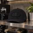 Black Stussy Pill Logo Snapback cap, a stylish headwear accessory featuring the iconic Stussy branding and adjustable snap closure.