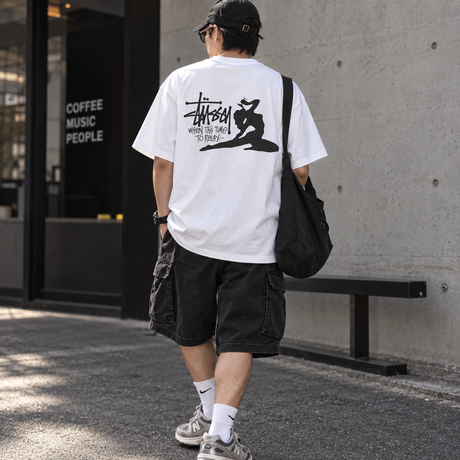 White Stussy Relax Tee shirt with a casual fit, displayed on a hanger, showcasing the relaxed style and soft cotton fabric.
