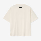 Cream Fear of God Essentials X NBA 90s heavyweight T-shirt displayed on a hanger, showcasing the relaxed fit and bold graphic print.