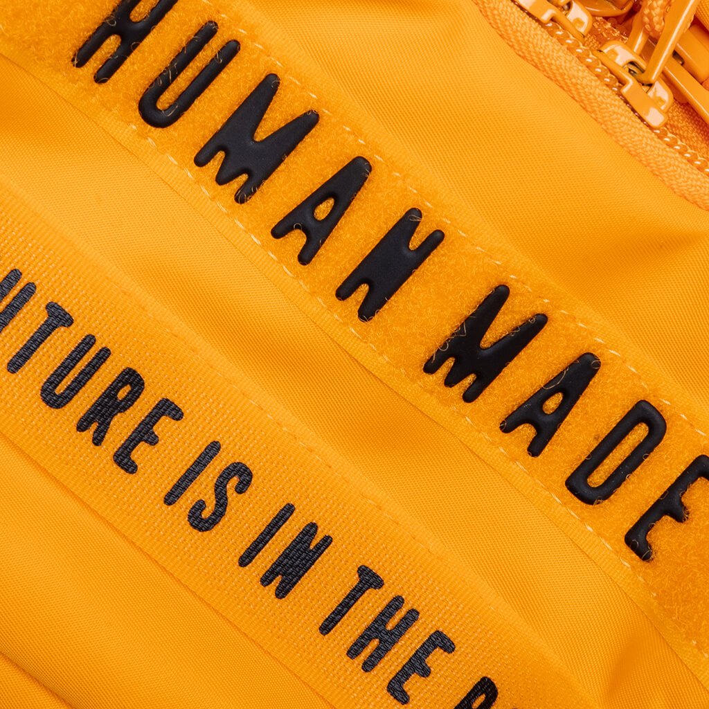 Yellow Human Made military mini sling bag with compact design and adjustable strap, ideal for casual or outdoor use.