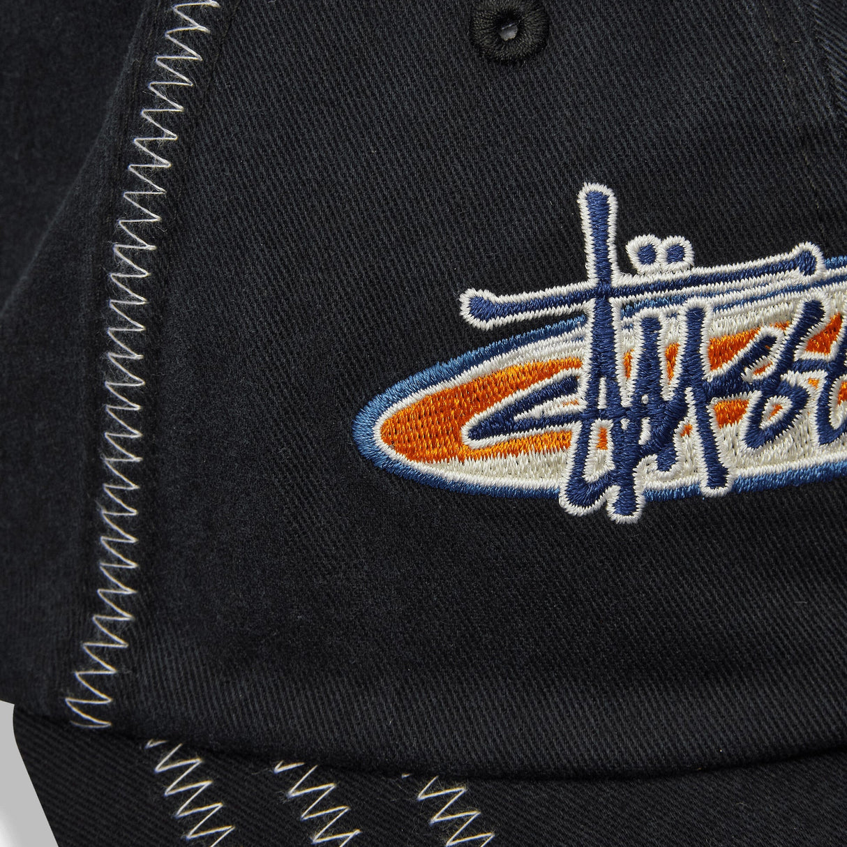 Black Stussy oval star cap, stylish headwear featuring the iconic star logo, shown from the front view.