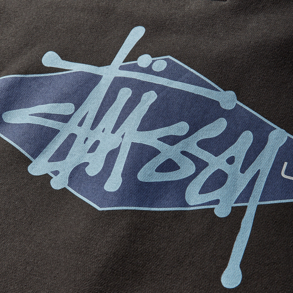 Black Stussy zip hoodie featuring a diamond logo design, made of comfortable apparel fabric with a front zipper and hood.
