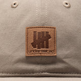 Undefeated Patch Logo Snapback hat in khaki with adjustable strap, canvas material, and branded patch detail.