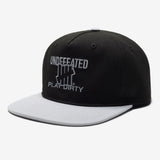 Black Undefeated Play Dirty snapback hat featuring bold branding and adjustable strap, styled as casual headwear.