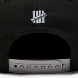 Black Undefeated Play Dirty Snapback hat, stylish headwear with embroidered branding, adjustable snapback closure, and flat brim.