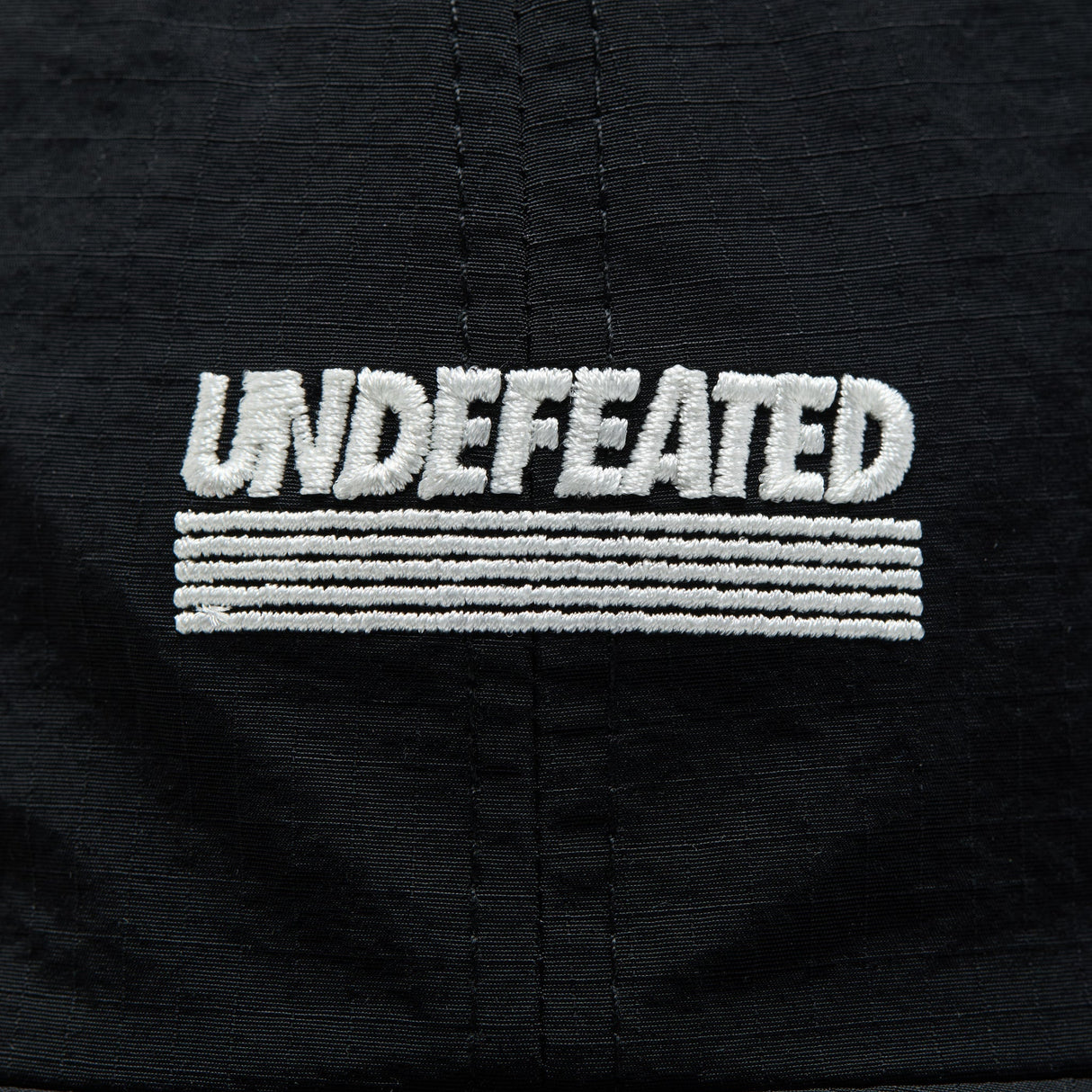 Black Undefeated Logo Strapback headwear with adjustable strap and embroidered branding on the front.