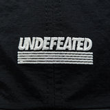 Black Undefeated Logo Strapback headwear with adjustable strap and embroidered branding on the front.