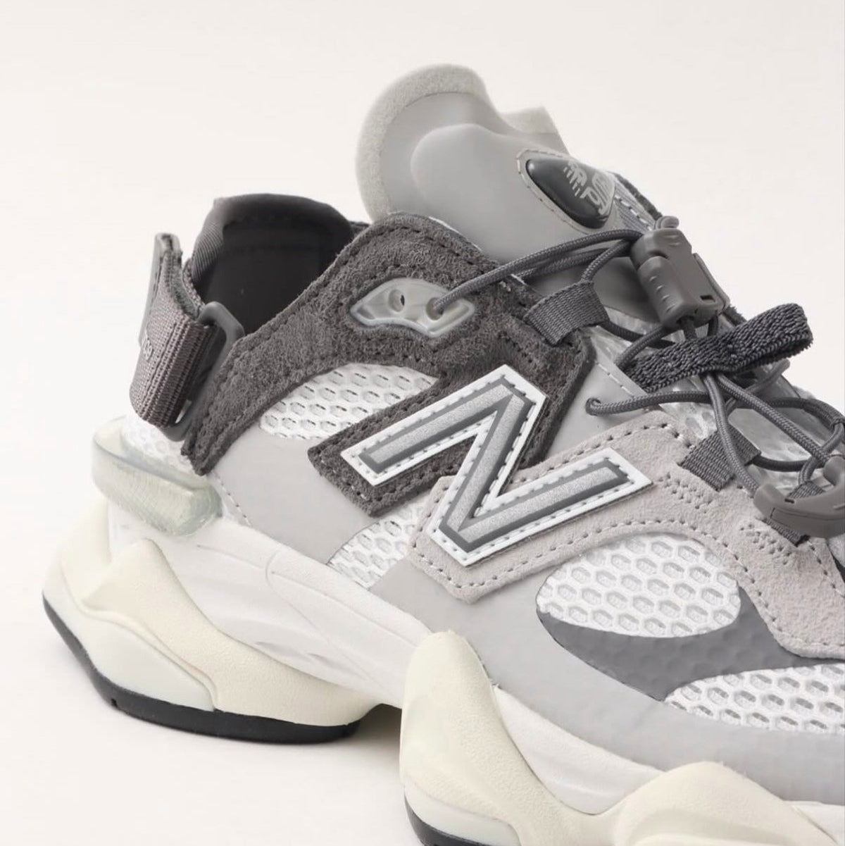 New Balance 9060 Mule Raincloud Castlerock sneakers with stylish design and textured gray material, indoor view.