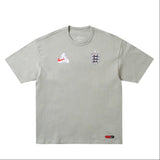 England Nike x Palace premium T-shirt in pewter grey featuring Nike branding and England graphic design.