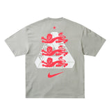England Nike x Palace premium T-shirt in pewter grey, featuring Nike and Palace branding and a stylish casual fit.