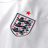 White Nike Palace x England tee shirt featuring England logo and branding, displayed flat with visible collar and graphic design.
