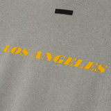 Fear of God Essentials x Lakers NBA 90s heavyweight tee in concrete, unisex T-shirt with Lakers logo and vintage 90s style.