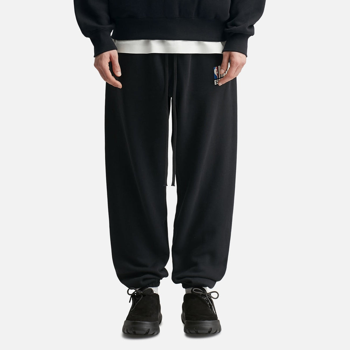 Black Fear Of God Essentials X NBA sweatpants with elastic waistband and logo detail, casual athletic apparel for men and women.