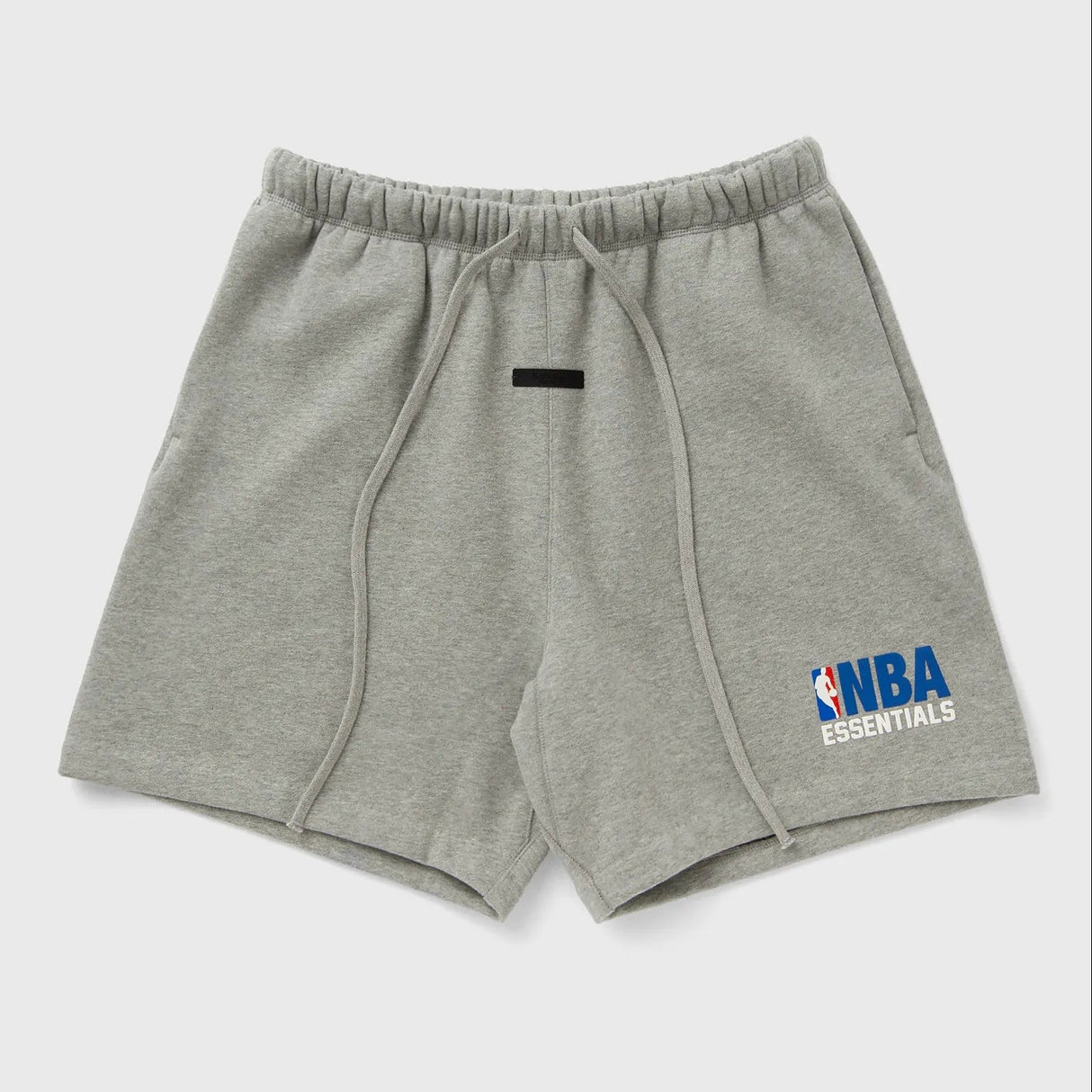 Fear of God Essentials NBA logo sweat shorts in concrete heather, featuring a relaxed fit and branded NBA patch on the side.
