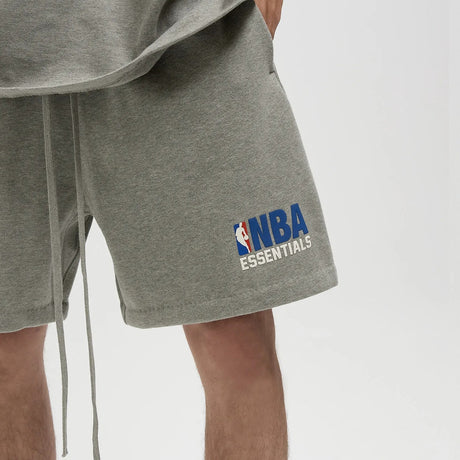 Fear Of God Essentials NBA logo sweat shorts in concrete heather, featuring relaxed fit and sporty design, casual apparel for everyday wear.