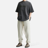 Fear of God Essentials Reflective Logo Ponte 90s Tee in Iron Dark Grey, showcasing a casual, sporty shirt with reflective logo detail.