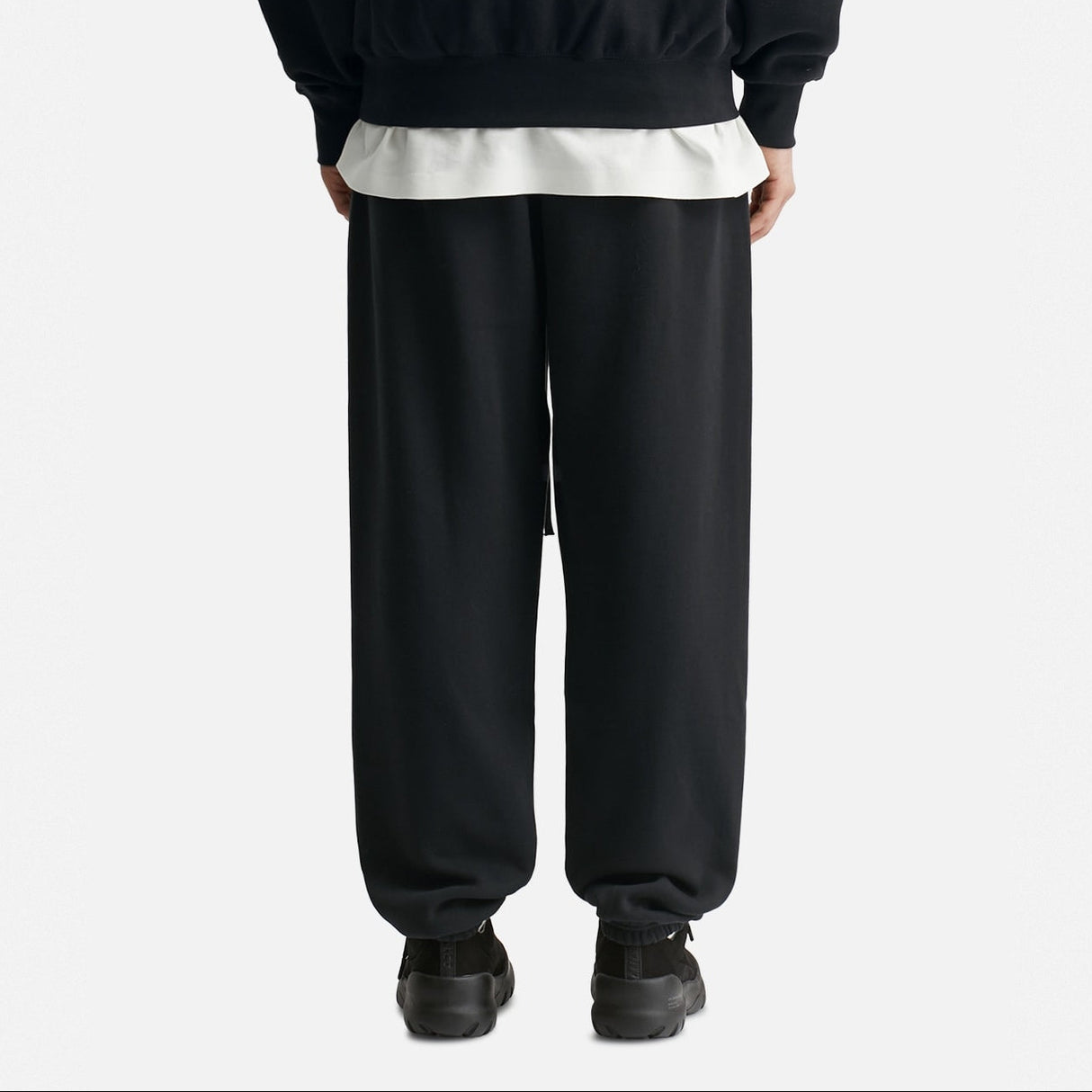 Black Fear of God Essentials x NBA sweatpants, casual apparel with logo details, shown laid flat on a white background.