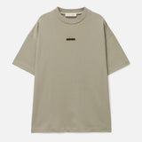 Fear of God Essentials metallic logo classic fit tee in Abbey Stone, showcasing a casual men's t-shirt with a metallic brand logo detail.