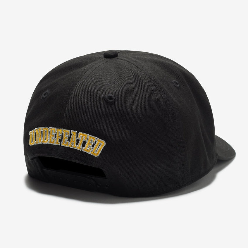 Black Undefeated 5 Logo snapback hat with flat brim and adjustable strap, featuring the brand's iconic logo on the front.