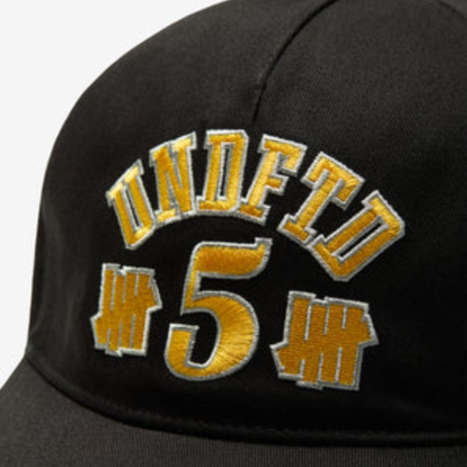 Black Undefeated 5 Logo snapback hat, stylish headwear with embroidered brand logo, adjustable brim, and flat top design.
